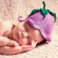 Baby mit Hütchen liegt schlafend auf der Seite