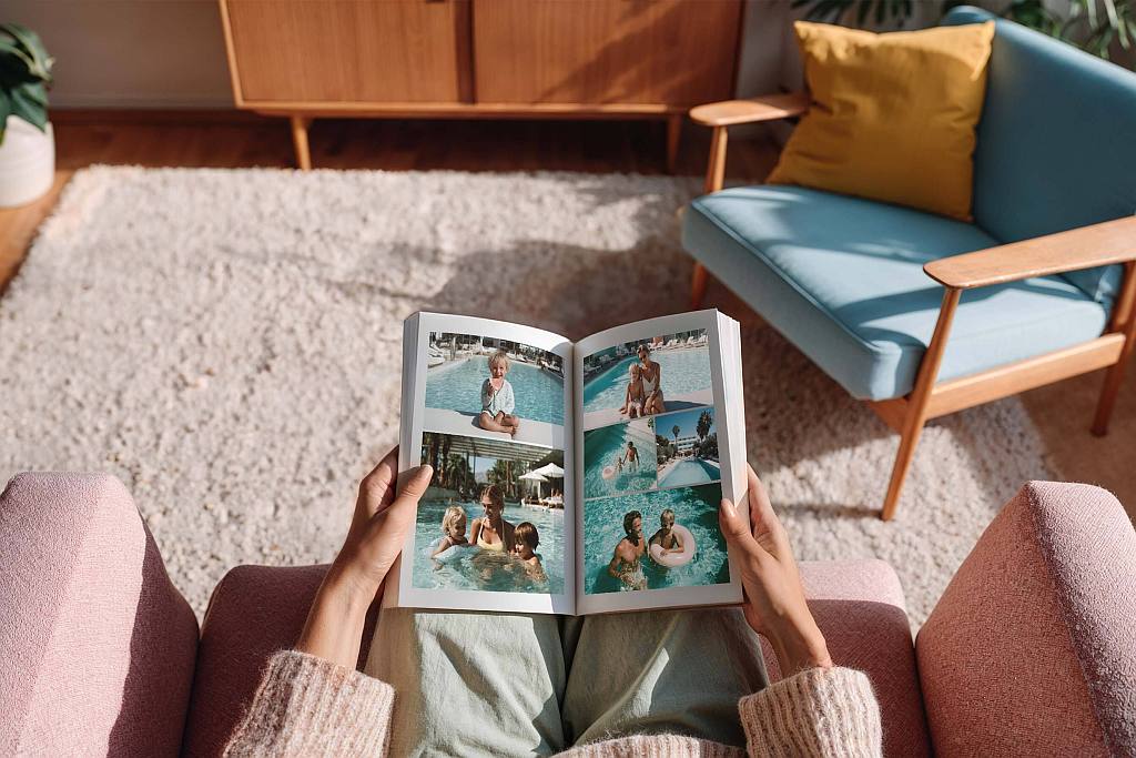 Fertig erstelltes KI-Fotobuch in den Händen einer Frau, die in einem Wohnzimmer sitzt.